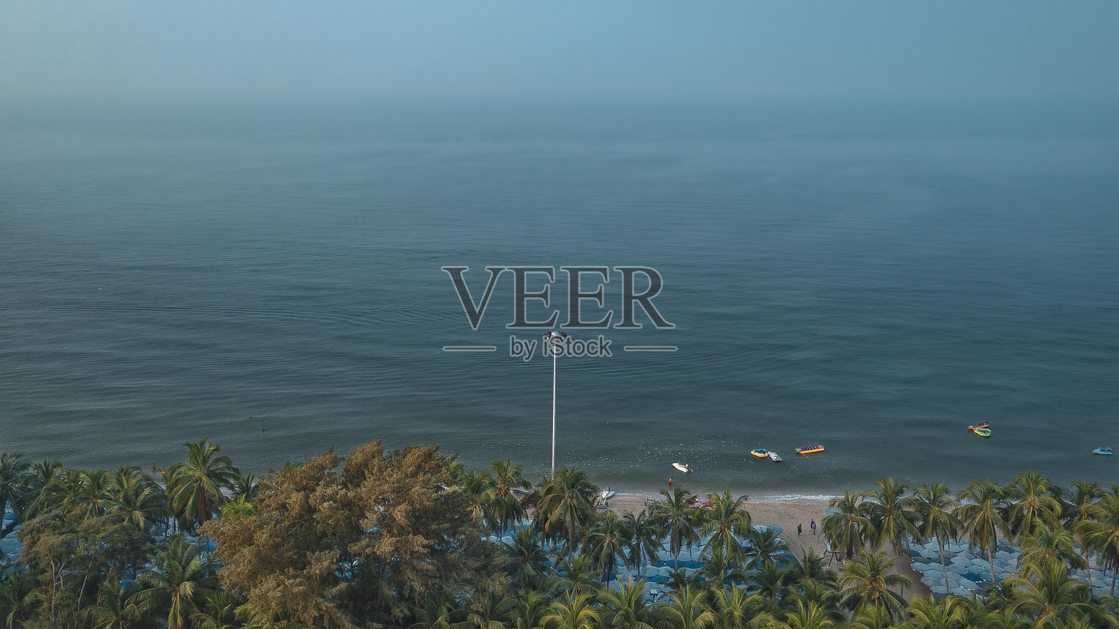 泰国春武里海岸地区的航拍图，展示了沙滩、椰子树和城市景观。照片摄影图片