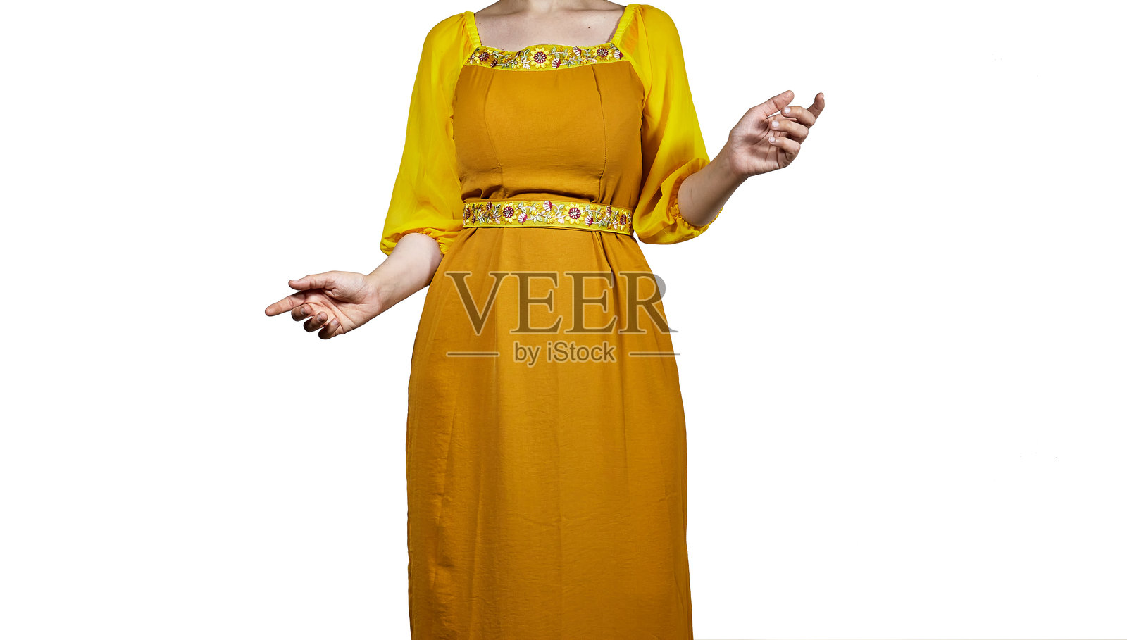 一位穿着鲜艳芥末黄色连衣裙的女性特写，连衣裙上有花卉刺绣和透明袖子，背景为纯白色。重点在于上半身和手臂。照片摄影图片