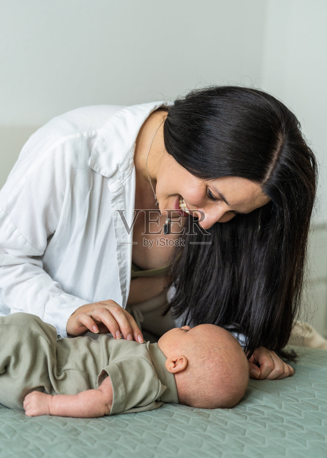 幸福微笑的母亲与她的新生儿的特写镜头。妈妈在享受温馨的家庭时刻时笑着，体现了母亲身份和育儿的概念。照片摄影图片