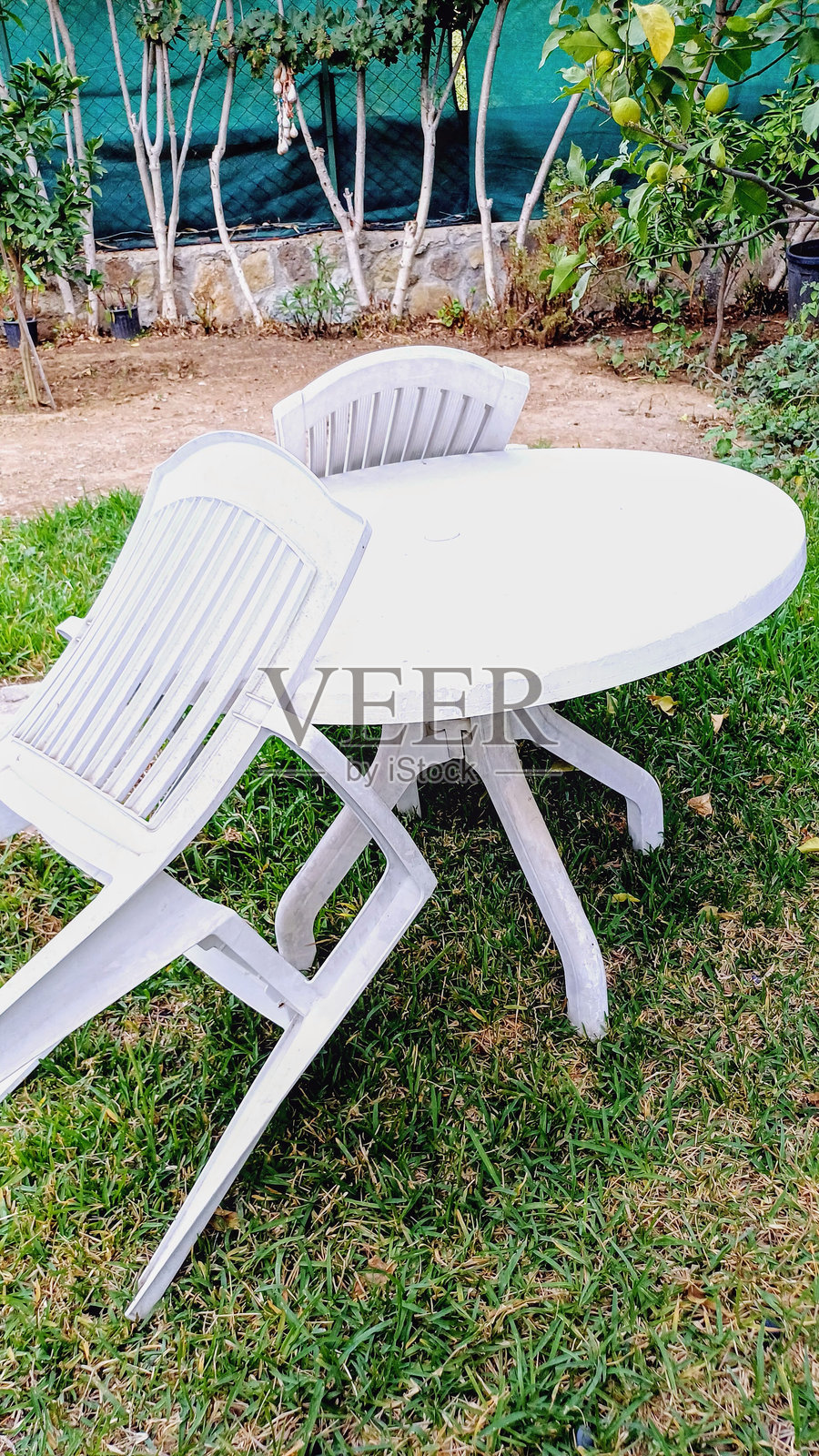 花园里的白色塑料桌椅。照片摄影图片