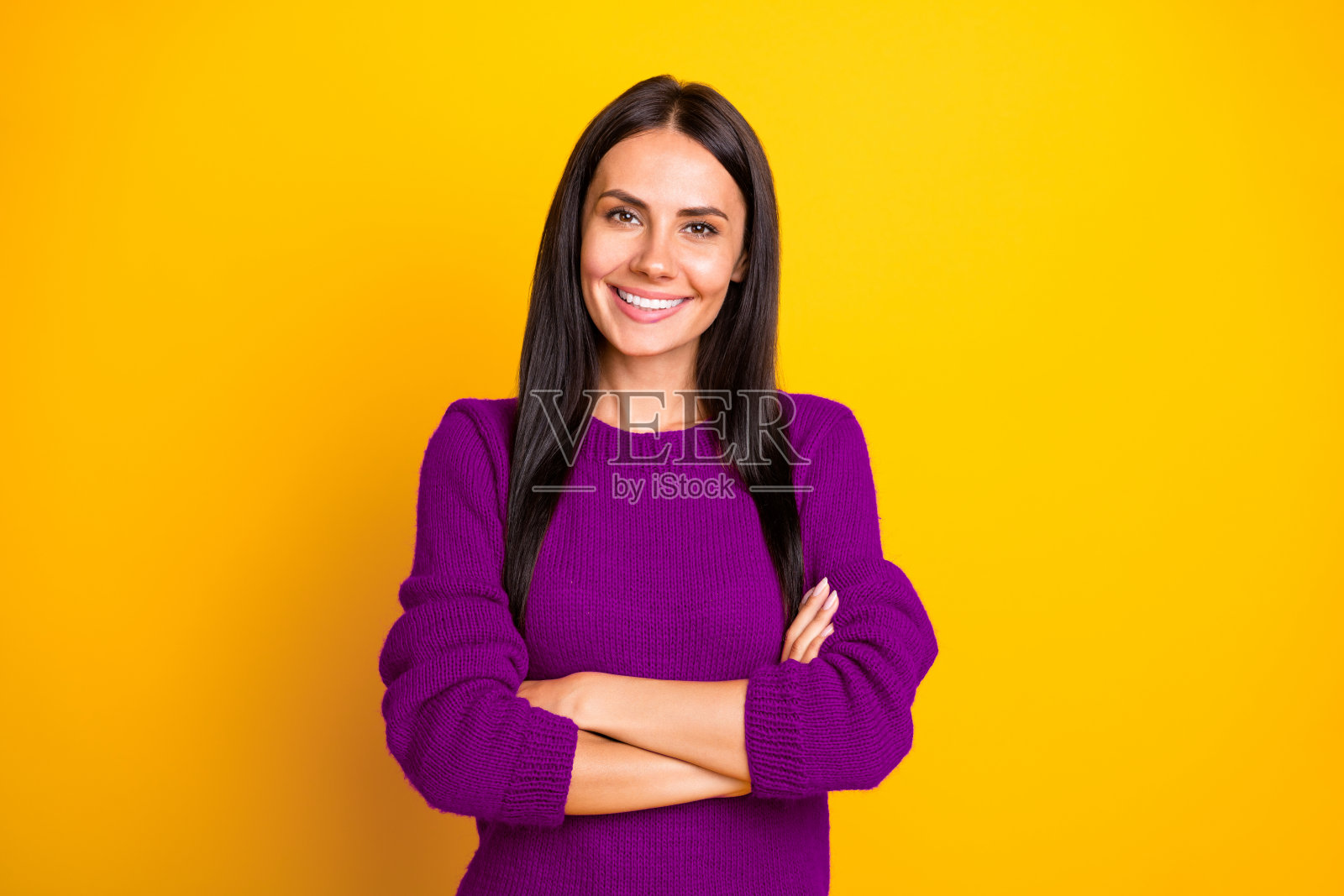 可爱的女士交叉双手，穿着红色现代毛衣，背景为黄色。照片摄影图片