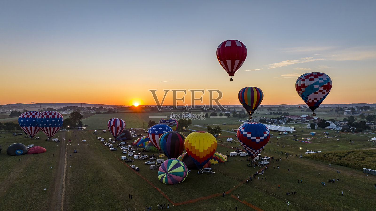 五彩缤纷的热气球在日落时分的热闹节日场景中起飞照片摄影图片