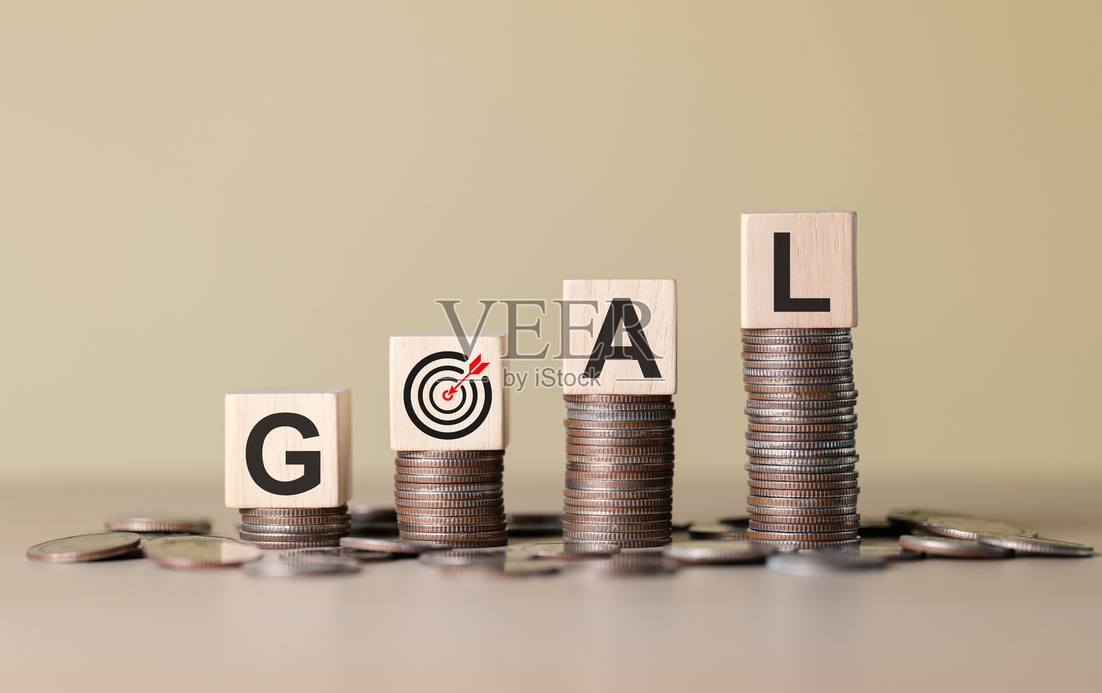 财务目标与储蓄概念。拼写“GOAL”的木块放在硬币堆上，旁边有一个目标图标，代表财务规划、储蓄、实现货币目标和商业增长。照片摄影图片