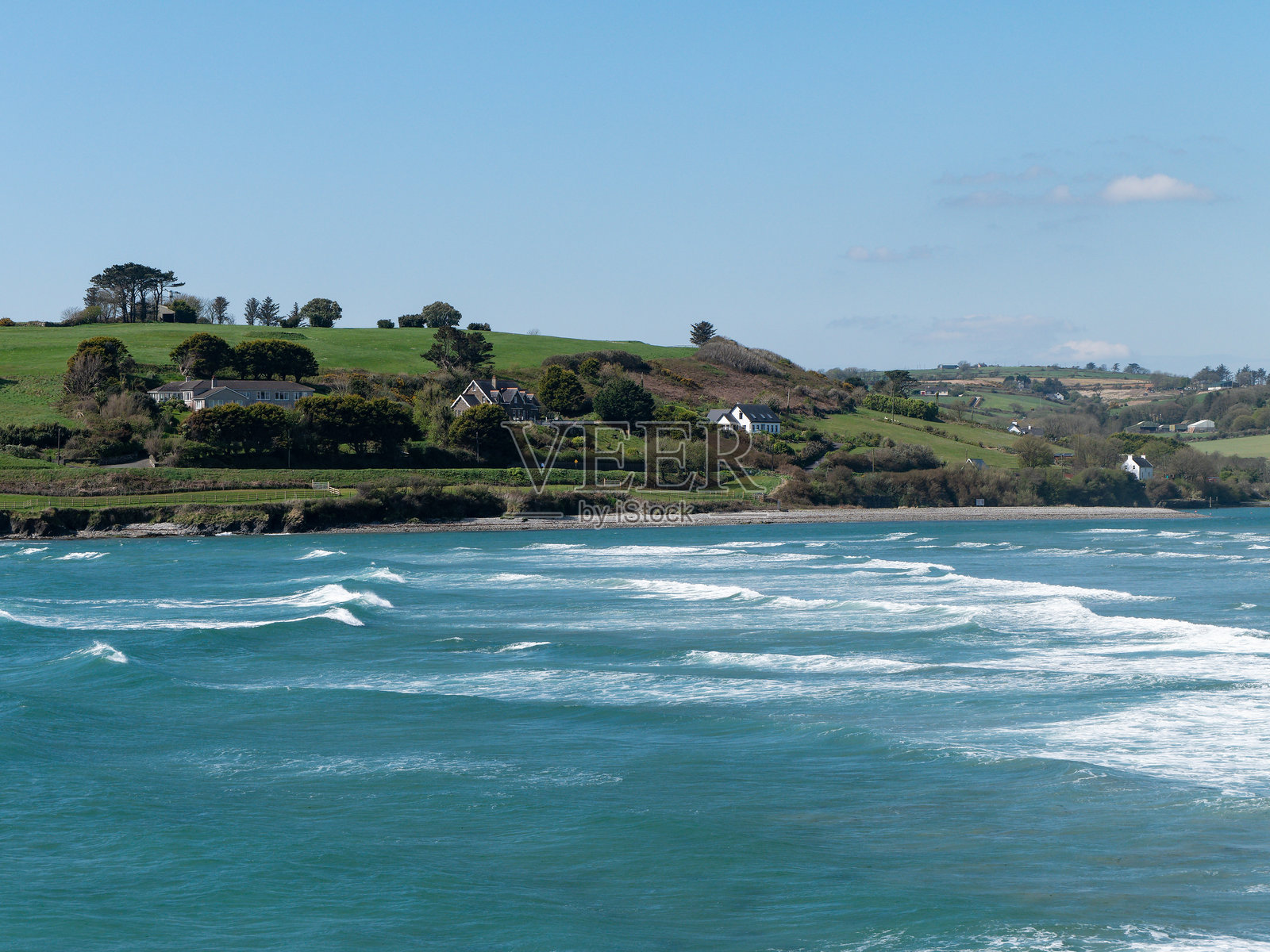 风景如画的海湾，白天。美丽的南爱尔兰自然风光。清澈天空下的大西洋蓝色海水。海岸风景。海浪拍打着海岸。照片摄影图片