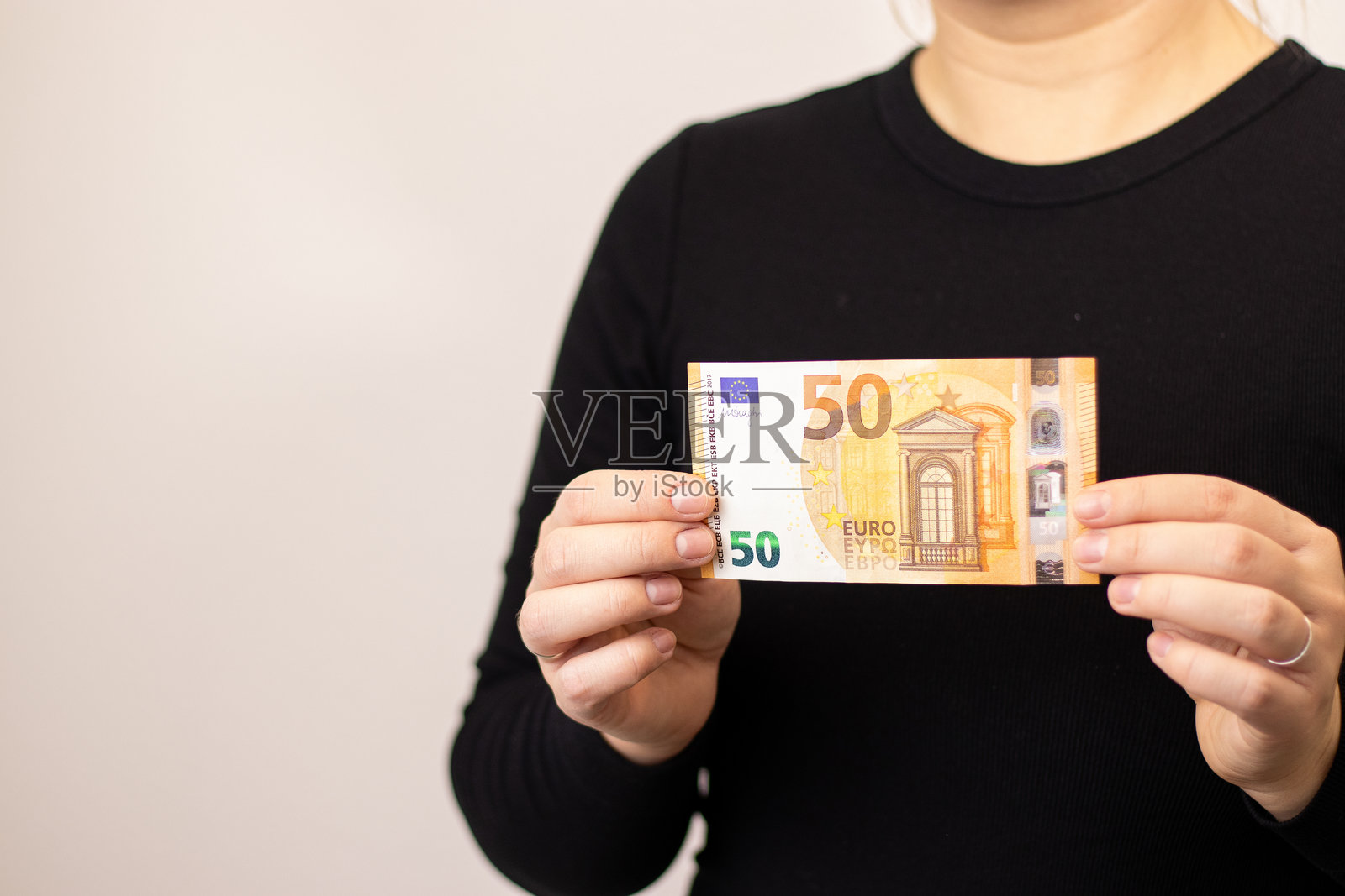 特写镜头：一位女性手持一张五十欧元钞票，背景为灰色。照片摄影图片