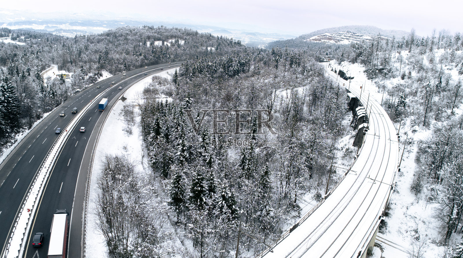 冬季森林中的平行雪覆盖高速公路和铁路照片摄影图片