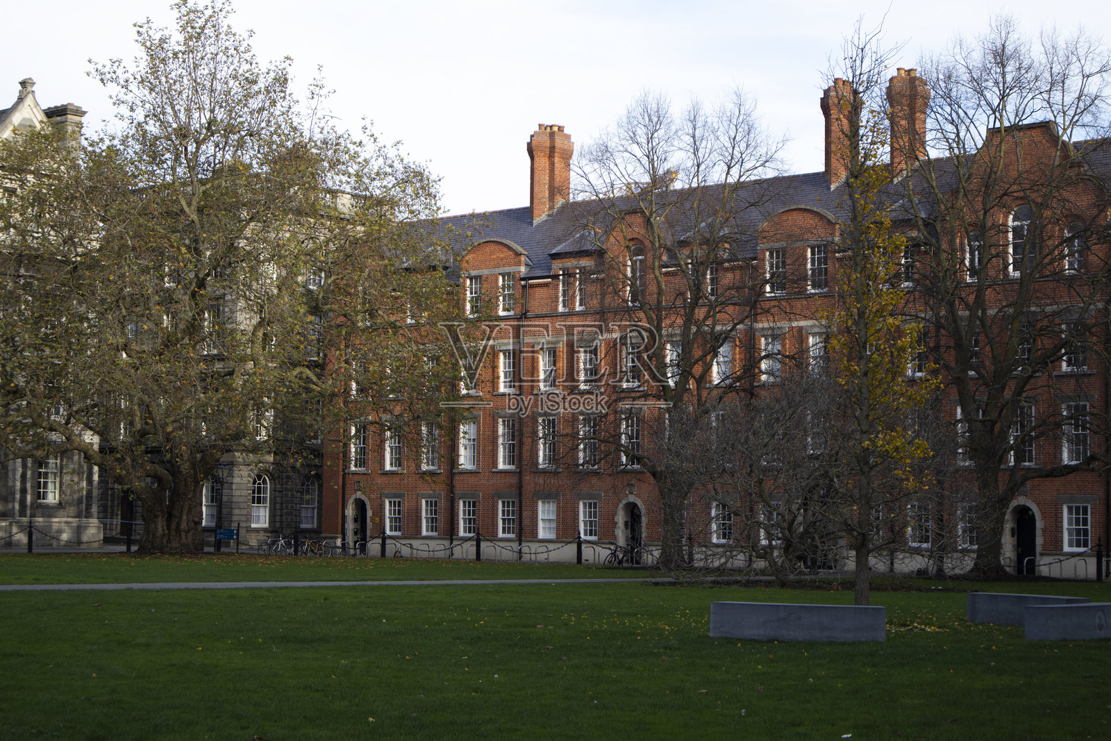 公园草坪之外是一座古老的红砖建筑。照片摄影图片