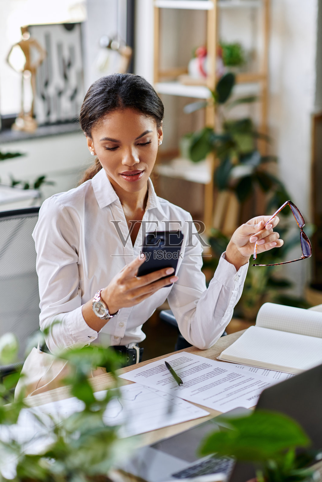 年轻的非裔美国女商人在现代办公室中使用智能手机照片摄影图片
