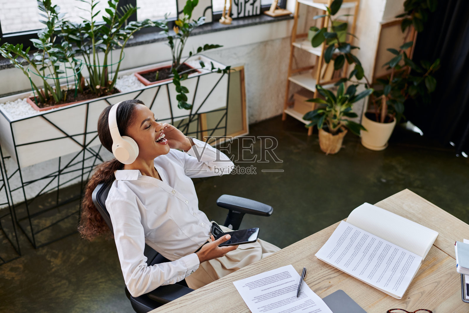 年轻的黑人女商人在热闹的办公室中享受工作和音乐照片摄影图片