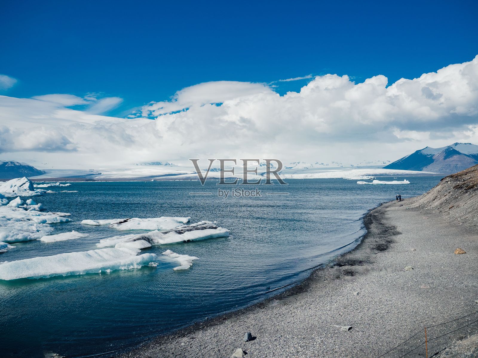 冰雪覆盖的风景，蓝色水域与白雪皑皑的山脉在晴朗的天空下交相辉映。照片摄影图片