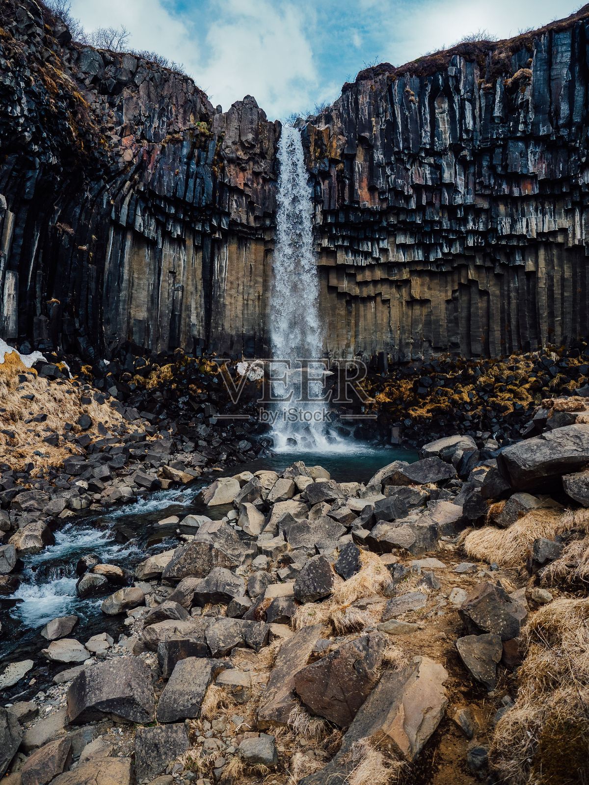 斯瓦尔蒂福斯瀑布从玄武岩柱上倾泻而下，周围是崎岖的岩石，展现出冰岛的壮丽景色。照片摄影图片