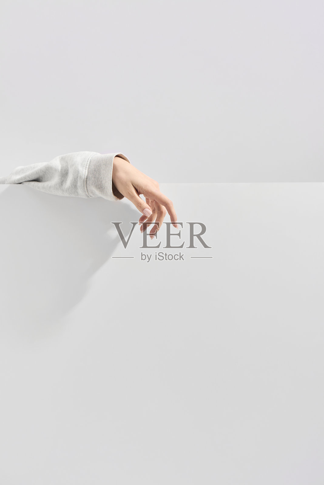 一只女性的手放在衣物上，背景为中性灰色。照片摄影图片