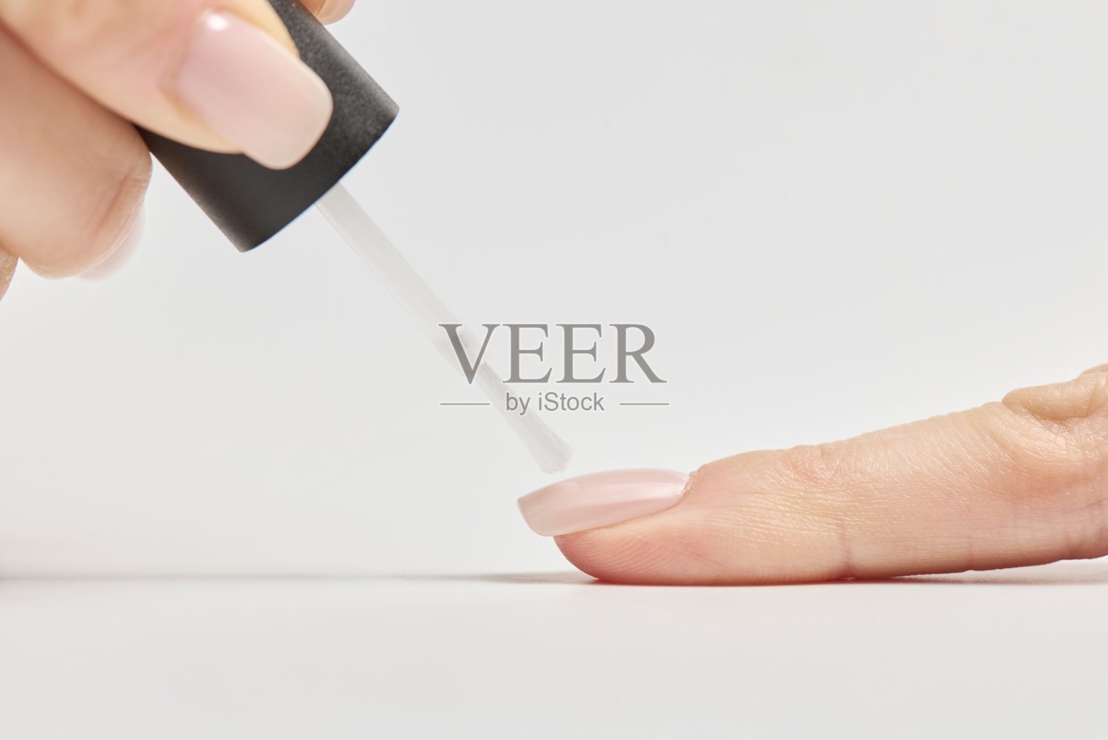 在简约的环境中进行放松的美容护理时，给指甲涂上浅色指甲油照片摄影图片