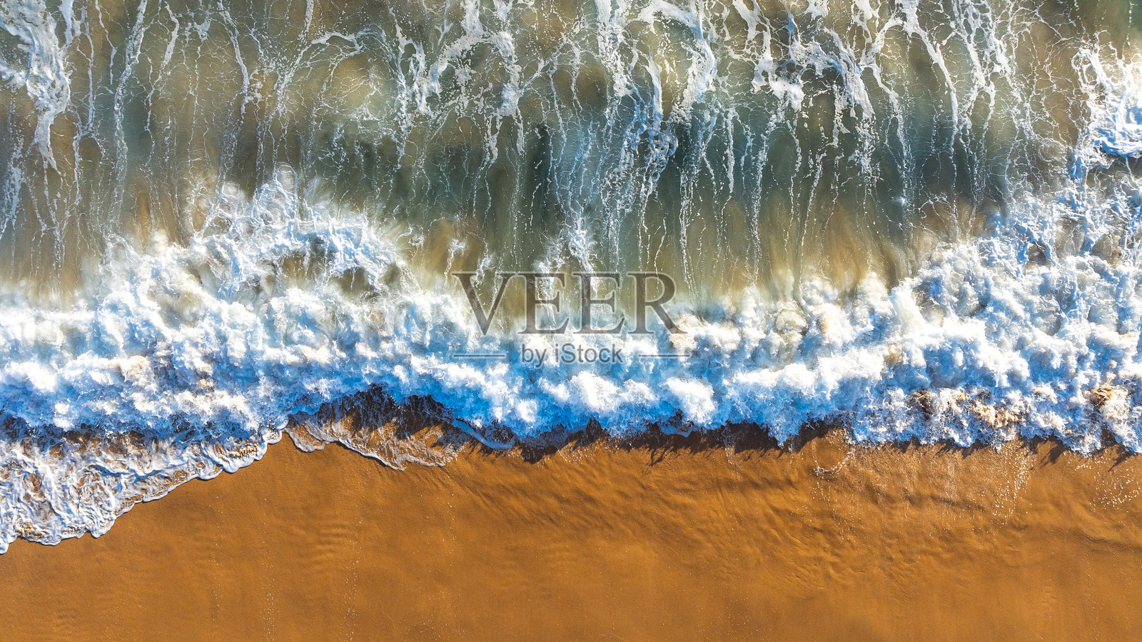 巨大的泡沫海浪涌向沙滩。阳光明媚的日子里，从上方俯瞰美丽的海岸。照片摄影图片