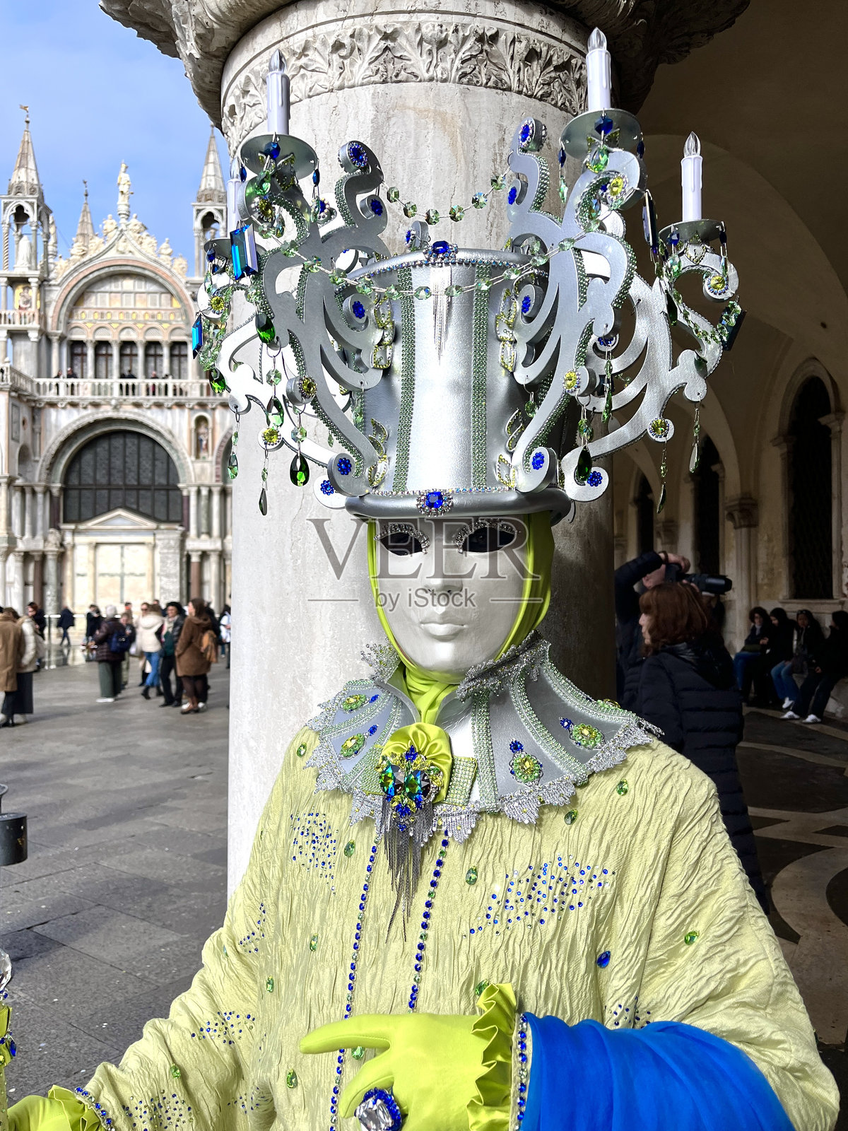 身穿华丽服装和面具的人在威尼斯狂欢节上靠近柱子摆姿势照片摄影图片