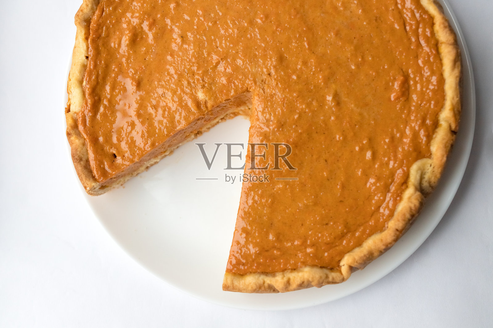 白色背景上的南瓜派，淋上焦糖酱。传统蛋糕。随时可以食用。烹饪概念。万圣节时光。照片摄影图片