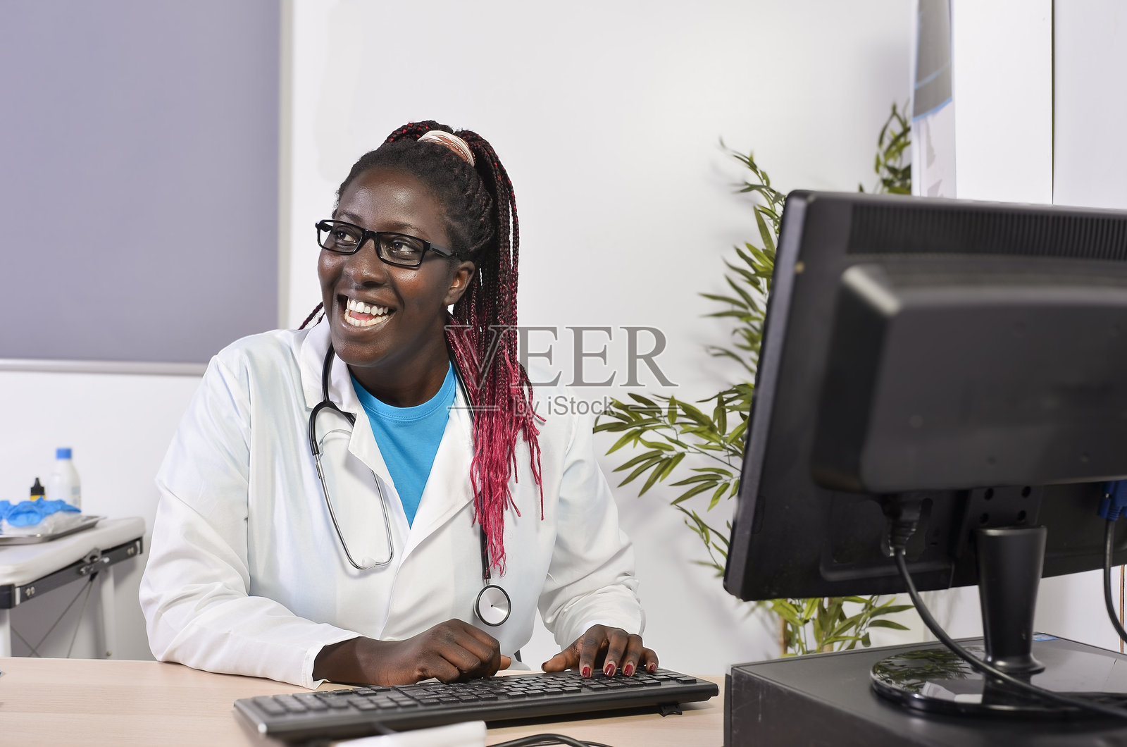 年轻医生在诊所微笑着使用电脑工作照片摄影图片