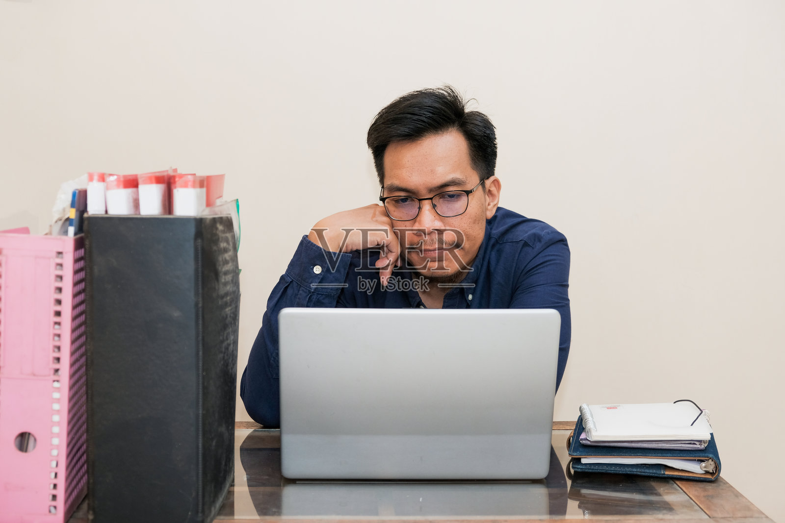 疲惫且压力重重的东南亚男子在家办公时坐在笔记本电脑前工作照片摄影图片