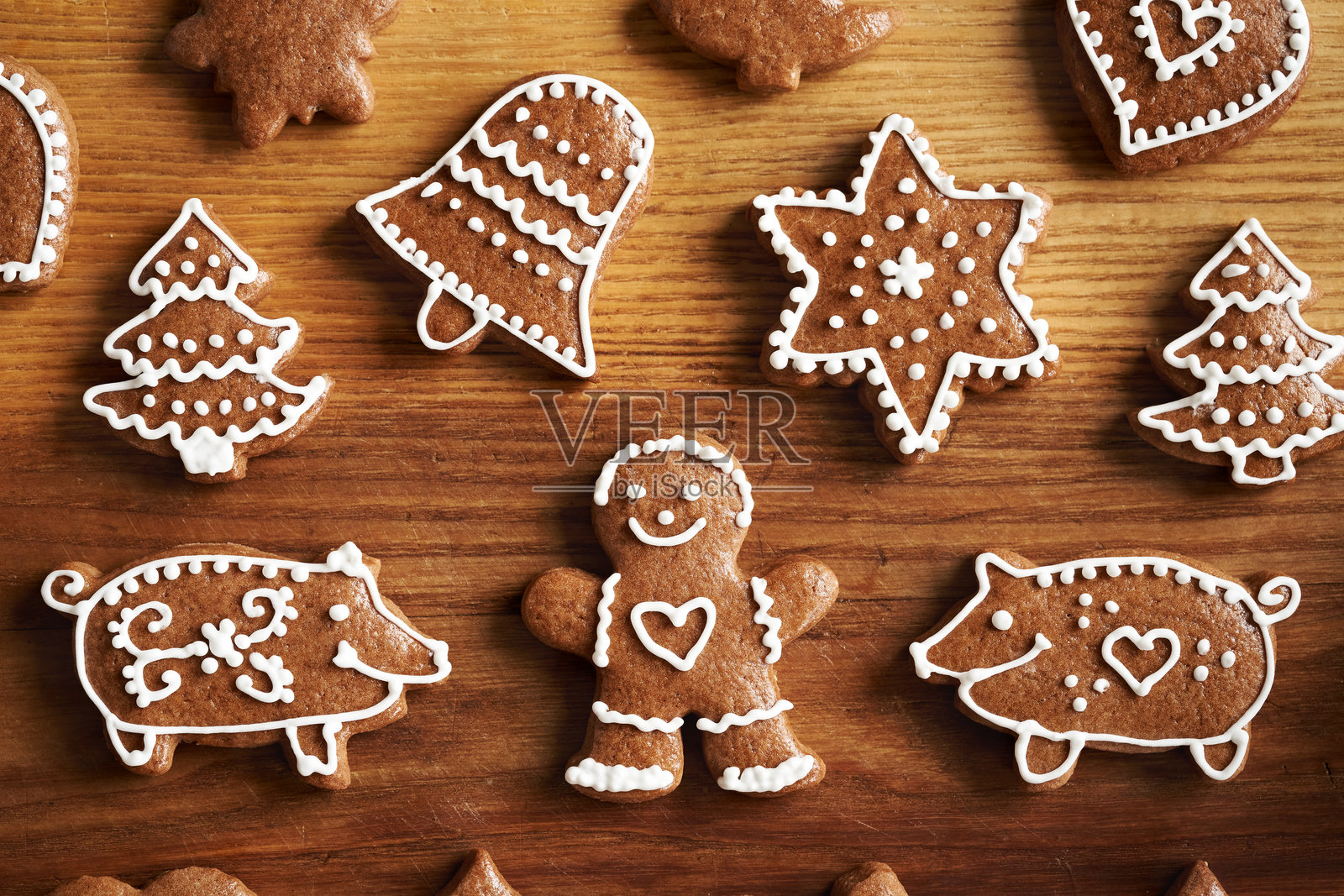 用白色糖霜装饰的自制姜饼圣诞饼干，形状为人和猪，摆放在木桌上照片摄影图片