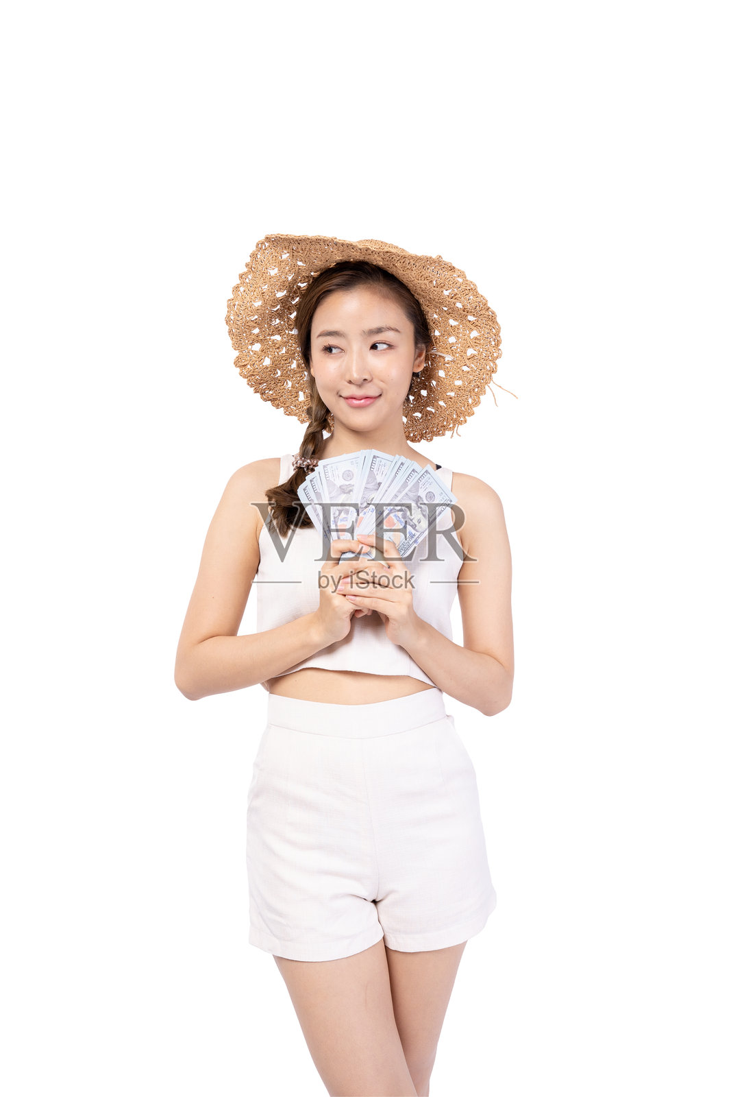 年轻女性戴着草帽，手持现金，背景为白色，展现出自信与风格。照片摄影图片
