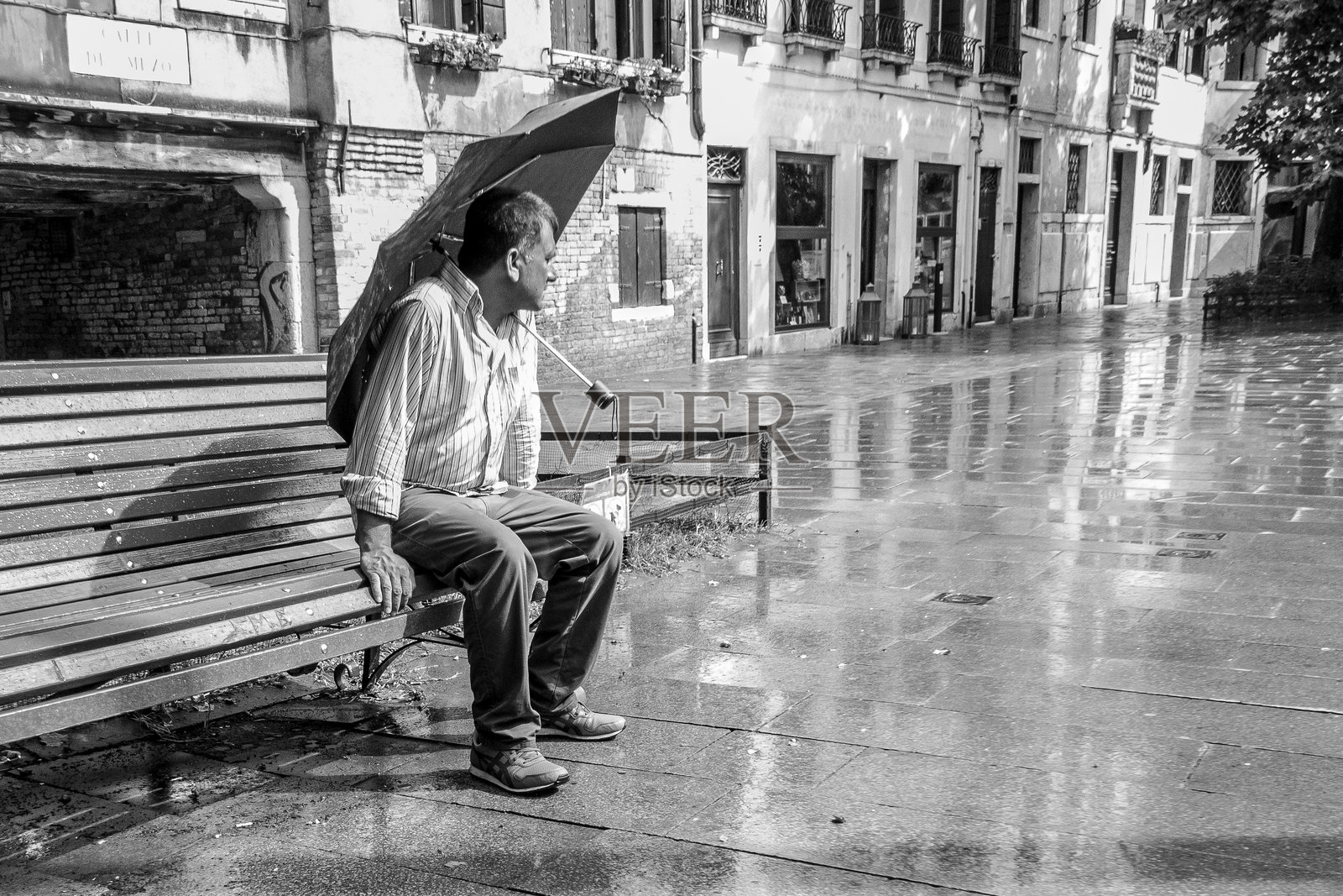 一个男人坐着，肩膀上搭着一把打开的雨伞照片摄影图片