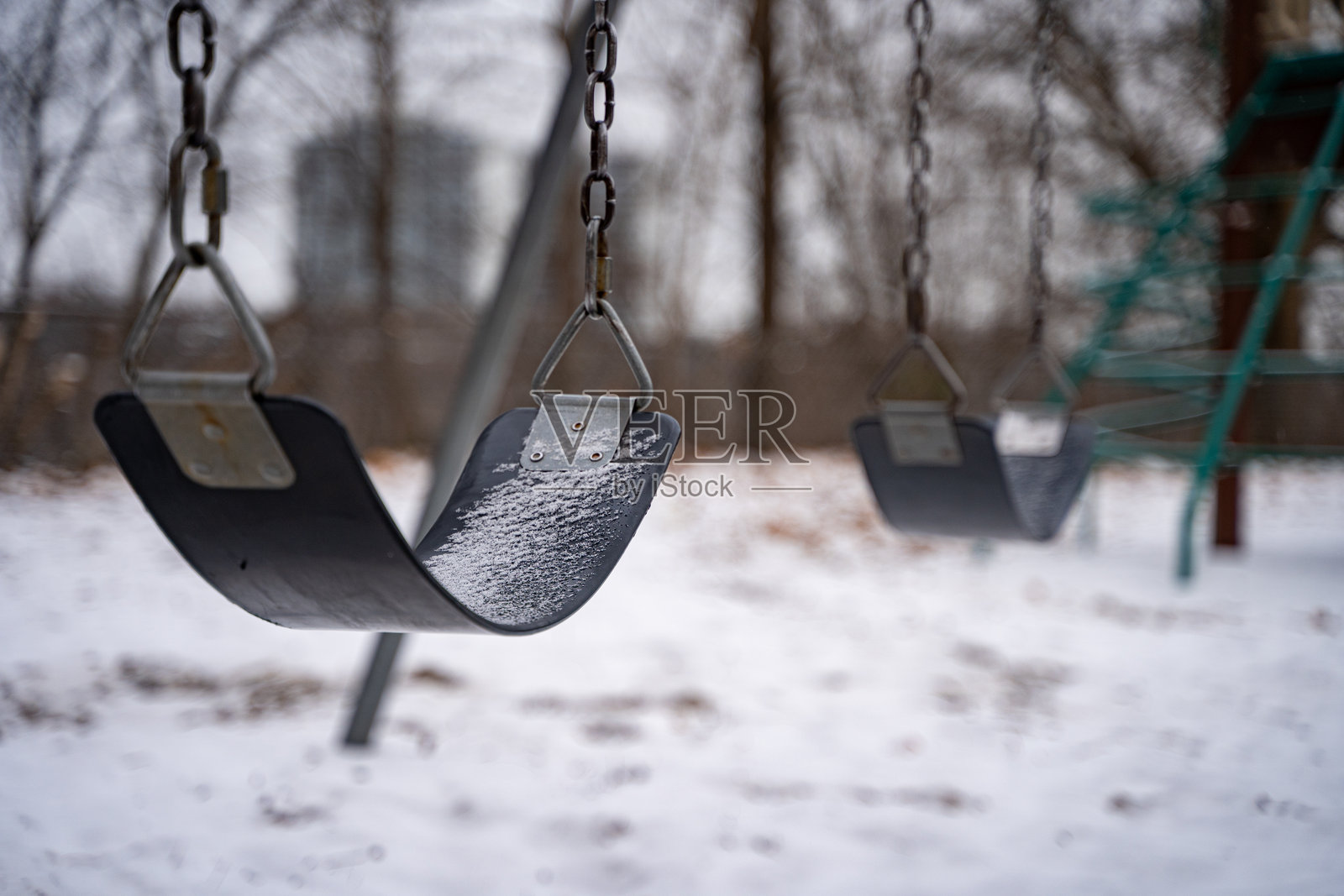 雪中的儿童游乐场秋千。照片摄影图片