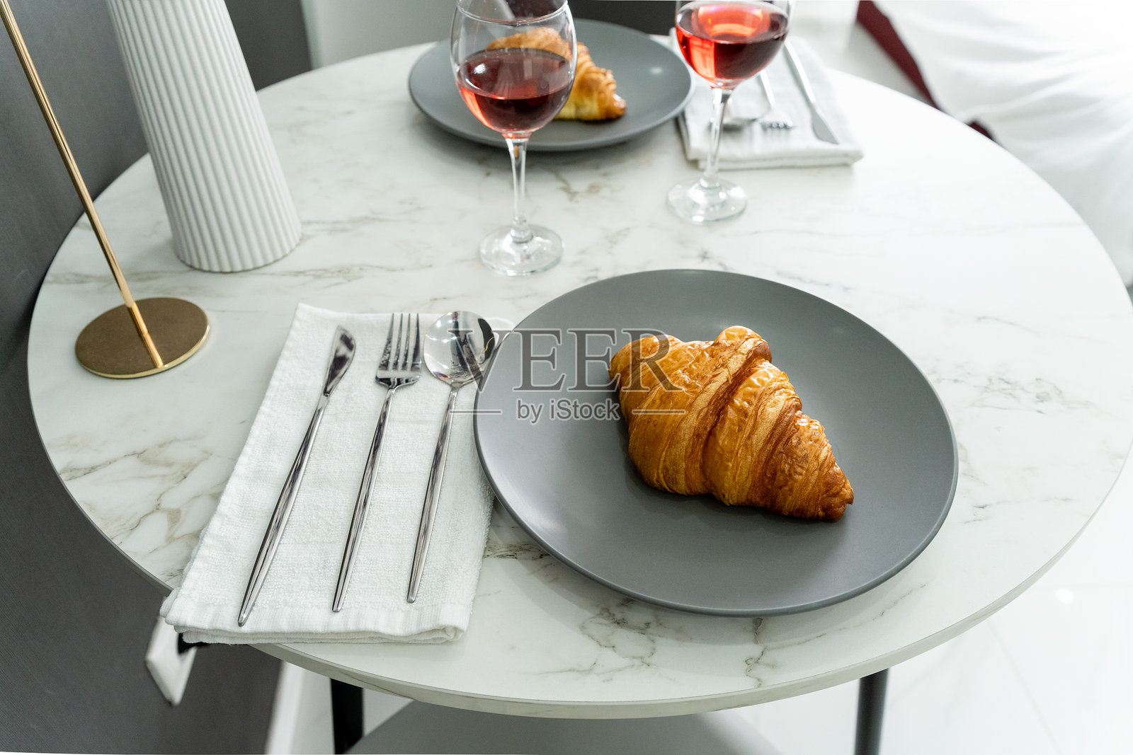 一个盘子上的可颂面包旁边放着酒，摆放在一个漂亮的桌子上照片摄影图片
