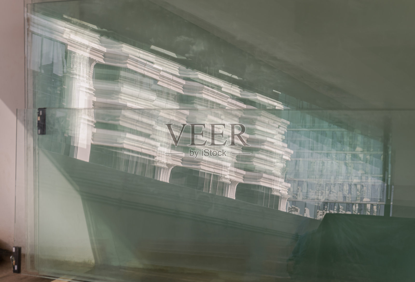 现代建筑图案在靠着水泥墙的反光玻璃板上的视图。照片摄影图片