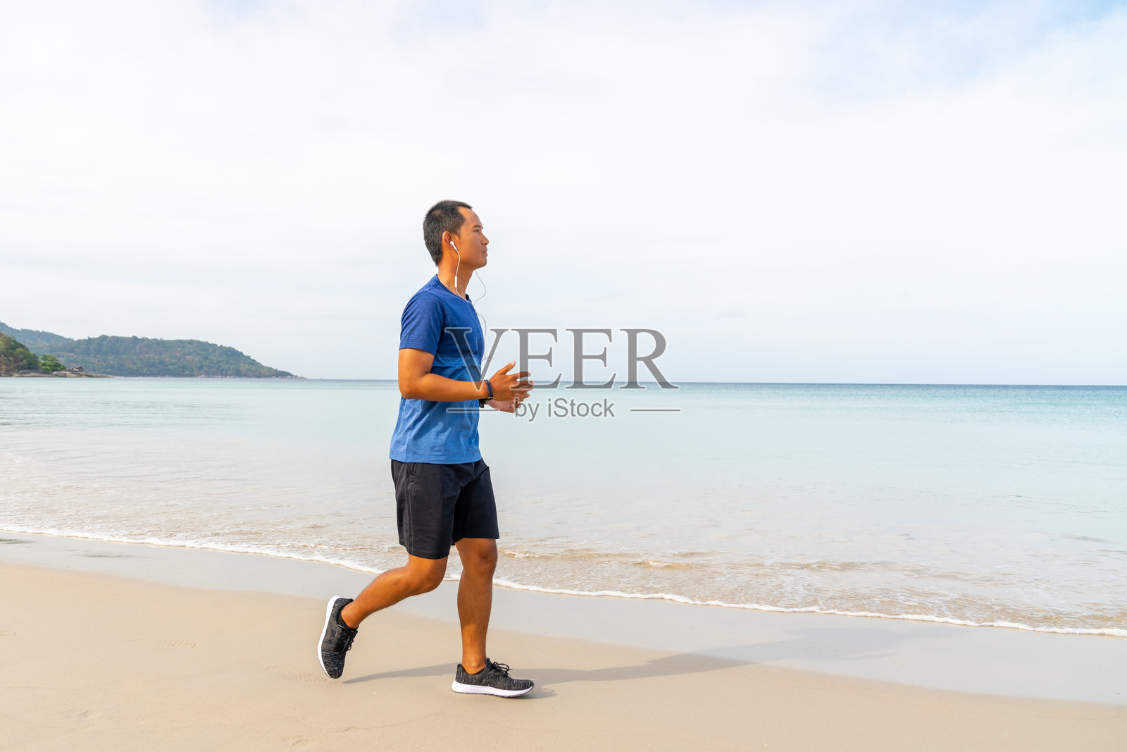 穿运动服的亚洲男子在海滩上慢跑照片摄影图片