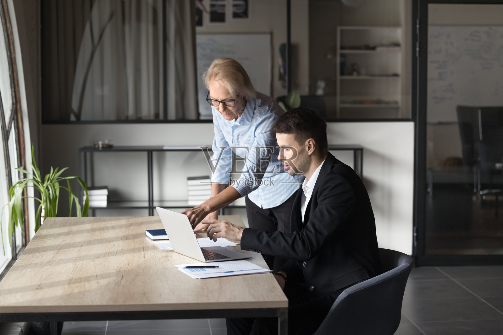 年长的导师帮助年轻员工完成任务照片摄影图片