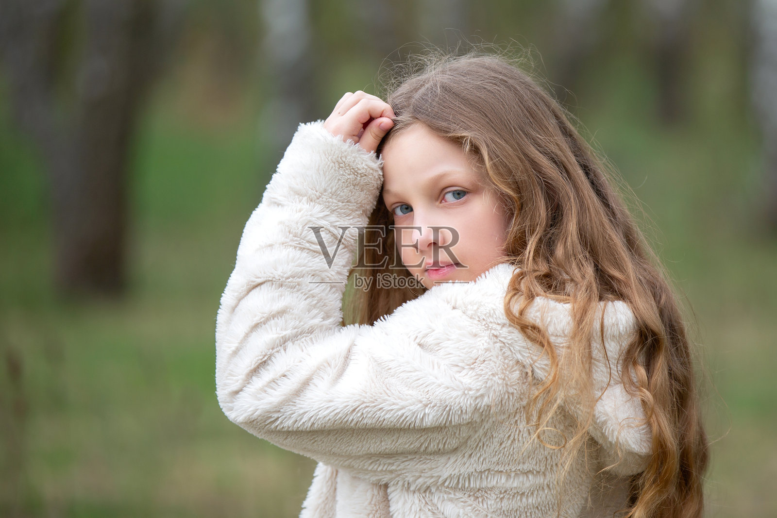 一位蓝眼睛的女孩，长着金色的头发，背景是自然风光。照片摄影图片