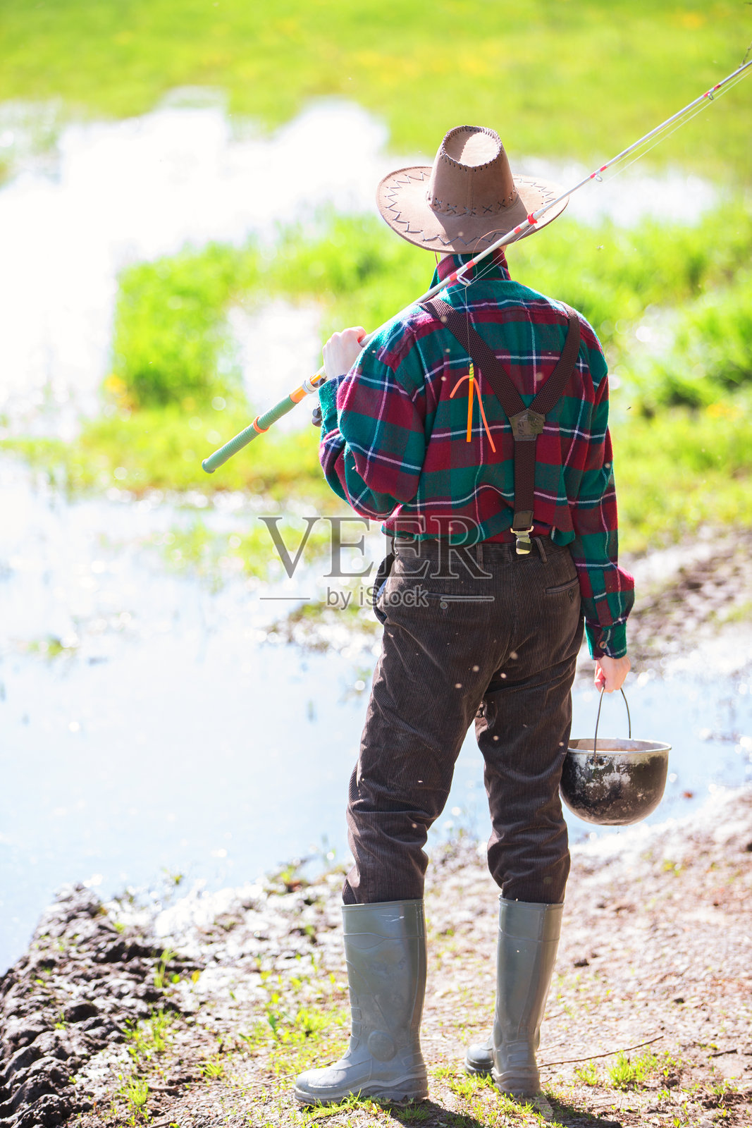 一位穿着橡胶靴的成年男子正准备去钓鱼。照片摄影图片