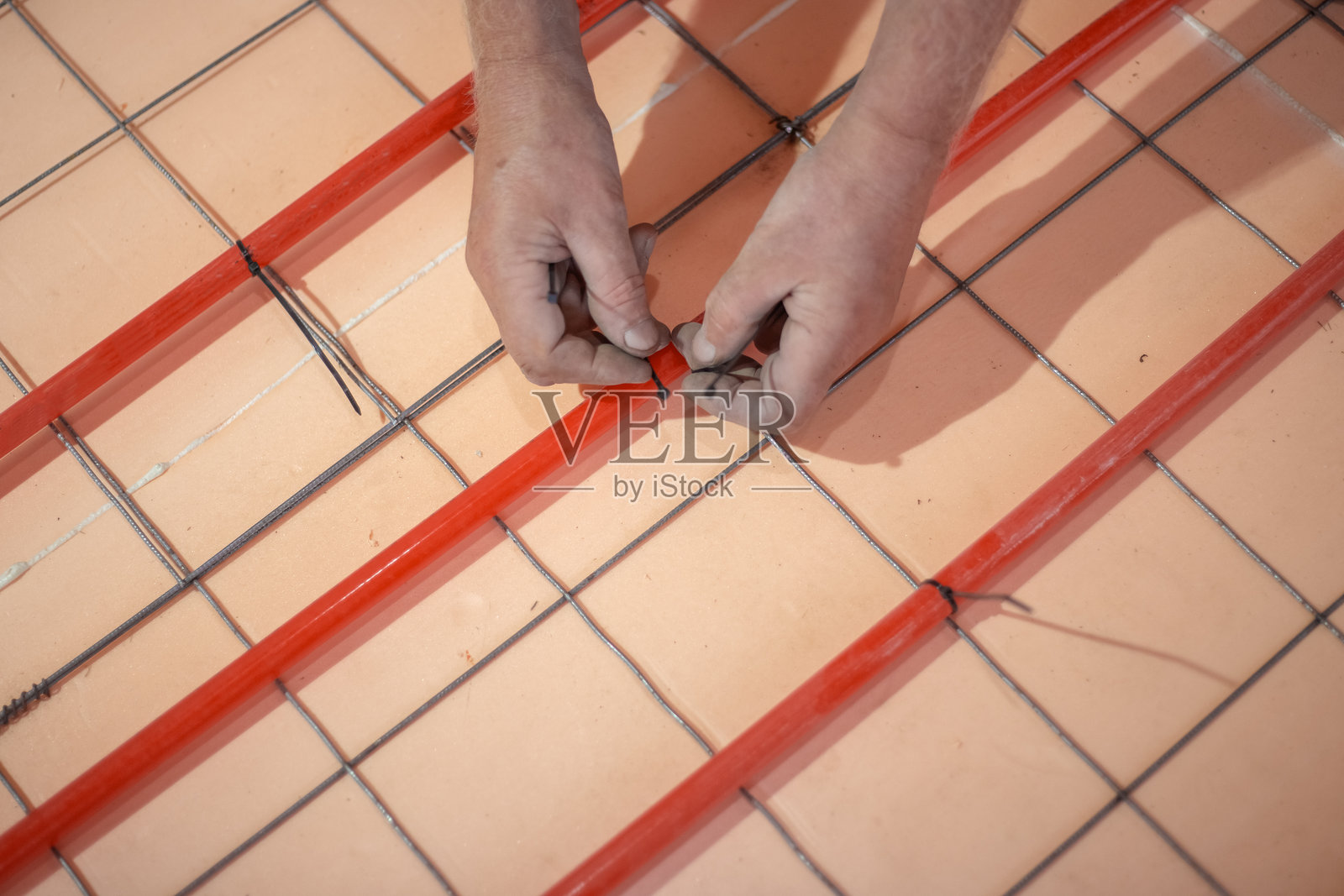 安装地暖。工人用夹子将交联聚乙烯制成的地暖管固定在加固网格上。照片摄影图片