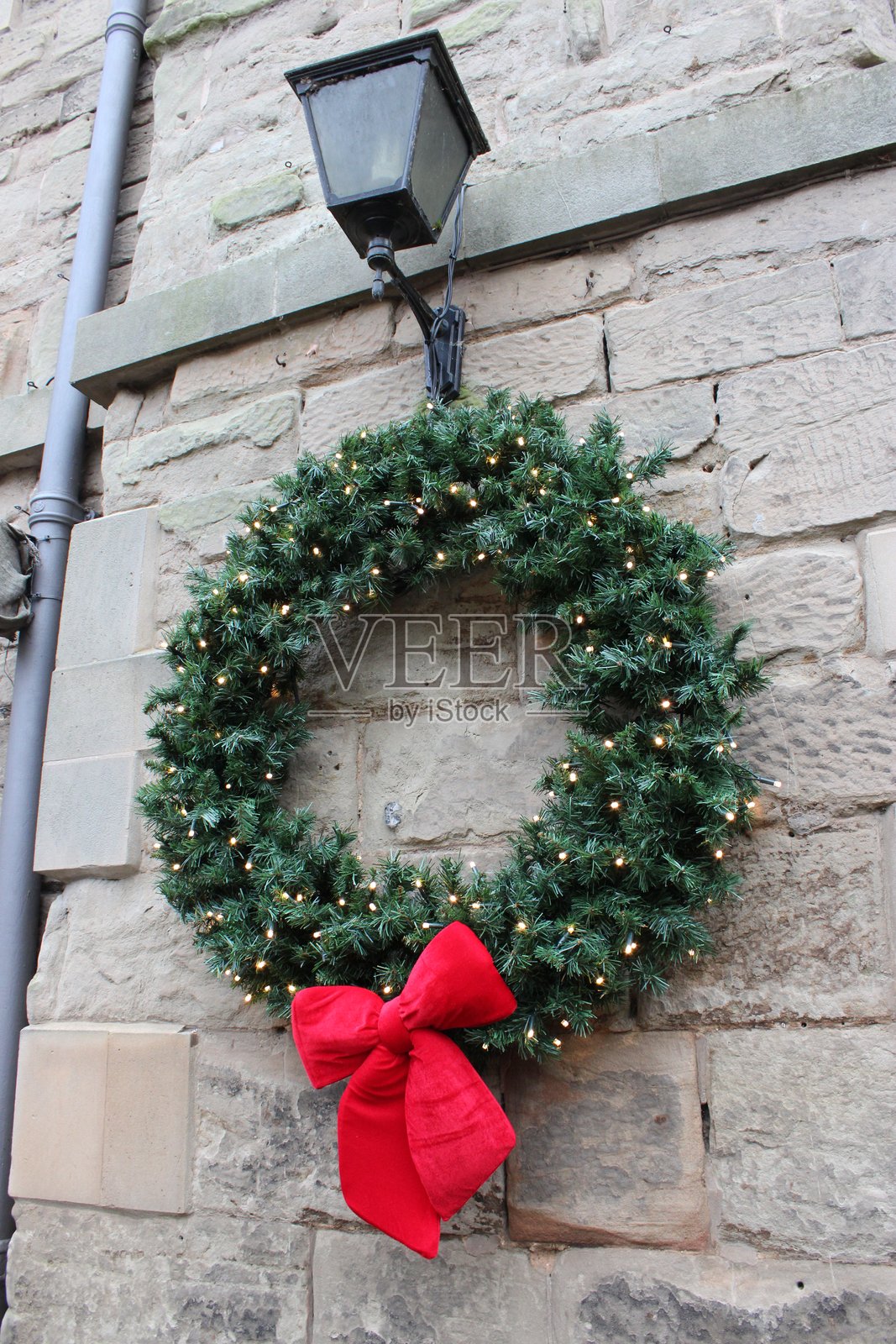 大型圣诞花环，配有红色蝴蝶结和灯光，白天拍摄。照片摄影图片