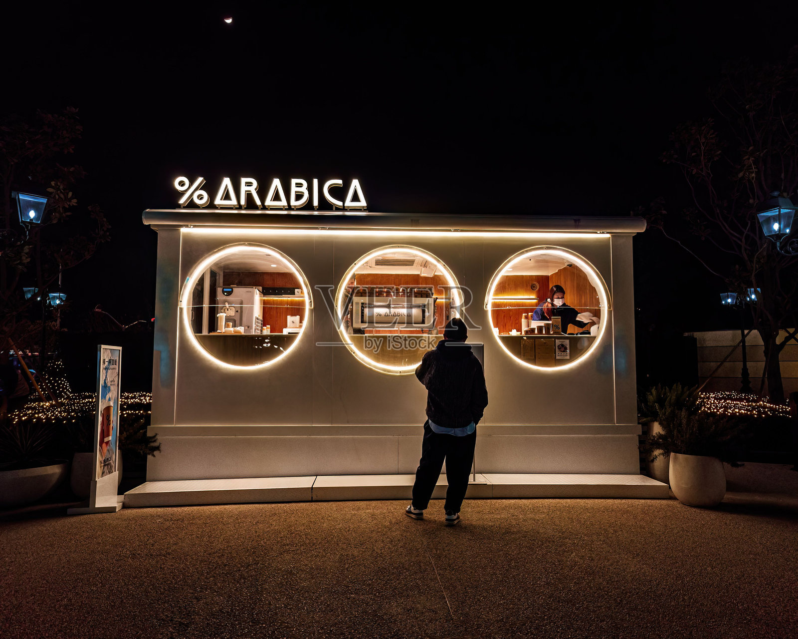 阿拉比卡品牌咖啡店在夜晚灯火通明。照片摄影图片