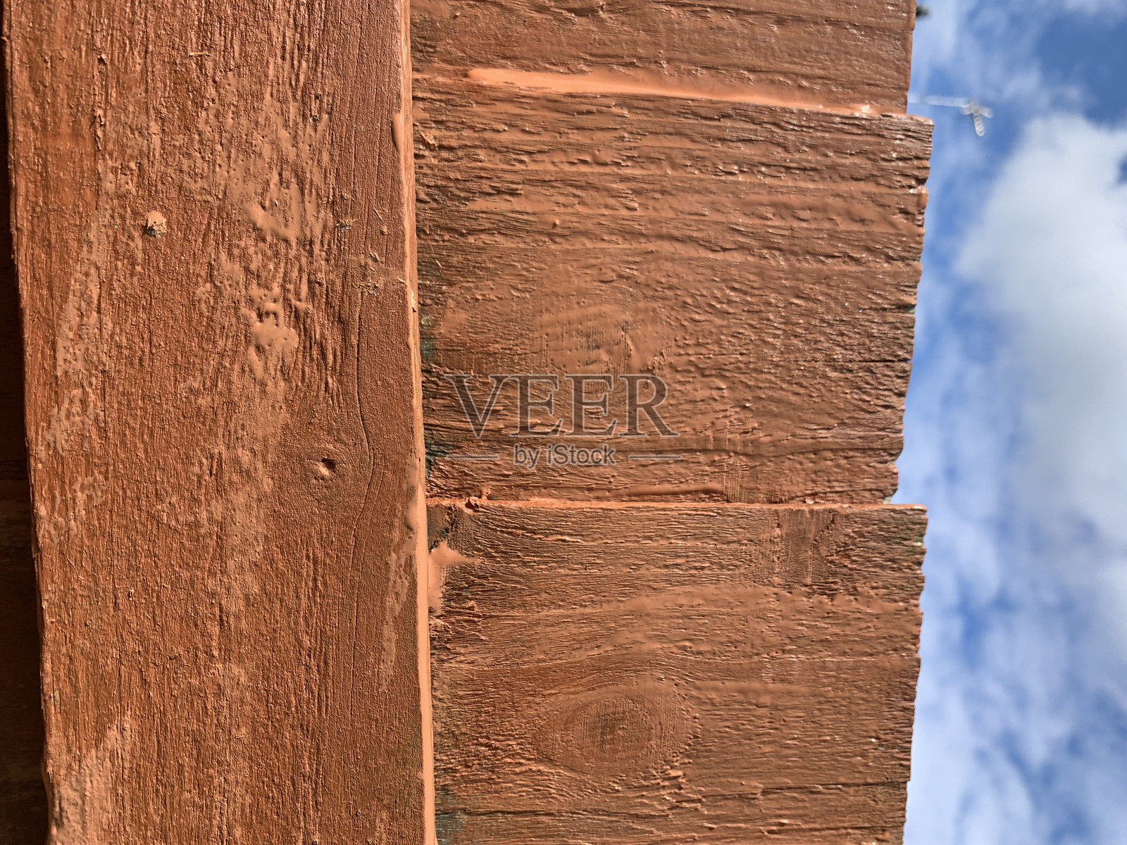 新刷的栅栏，湿漉漉的金栗色油漆，背景是蓝色多云的天空照片摄影图片