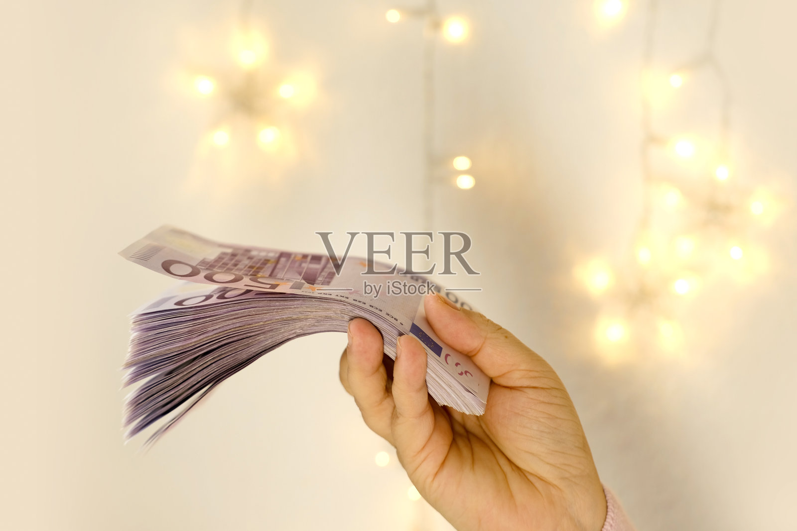 女性手中握着500欧元的钞票，背景模糊，呈奶油色，带有散景效果，薪水，支付资金，节日礼物，社会救助，存钱度假，购车，赌场中奖。照片摄影图片
