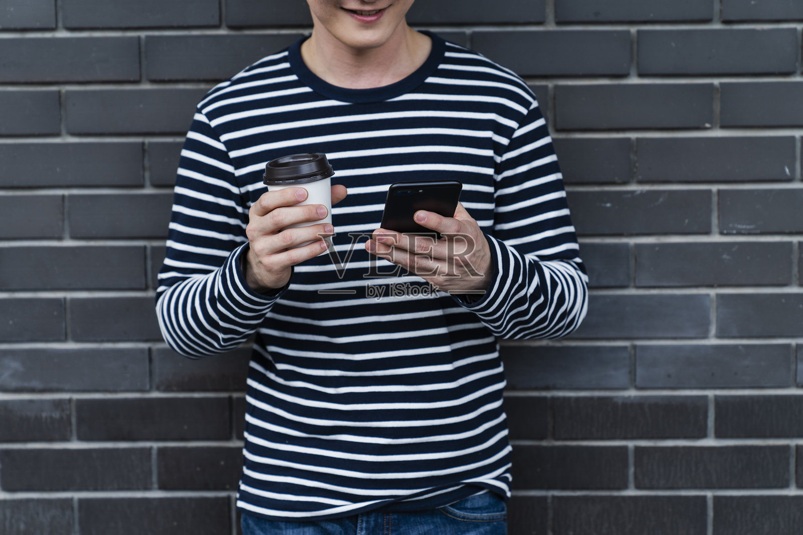 男子在砖墙前使用手机的中部特写照片摄影图片
