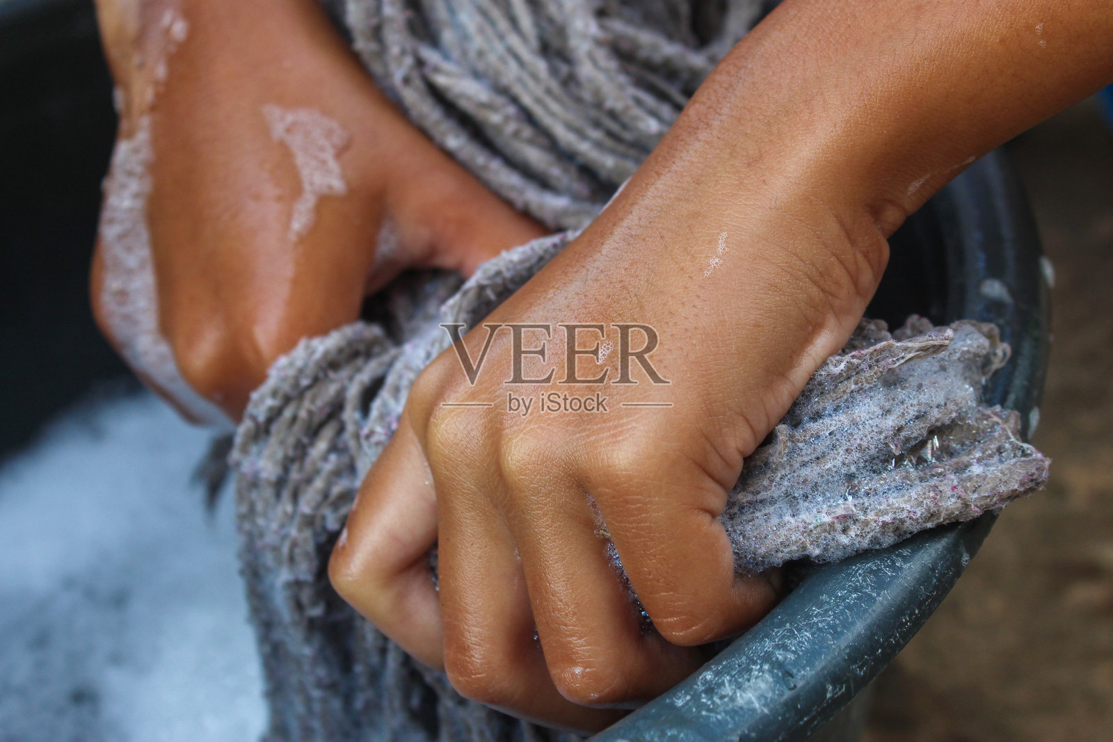 双手拧干满是泡沫的拖把照片摄影图片