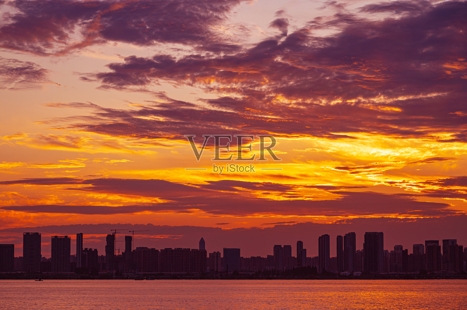 日落时分，现代城市天际线下的戏剧性天空和云彩照片摄影图片