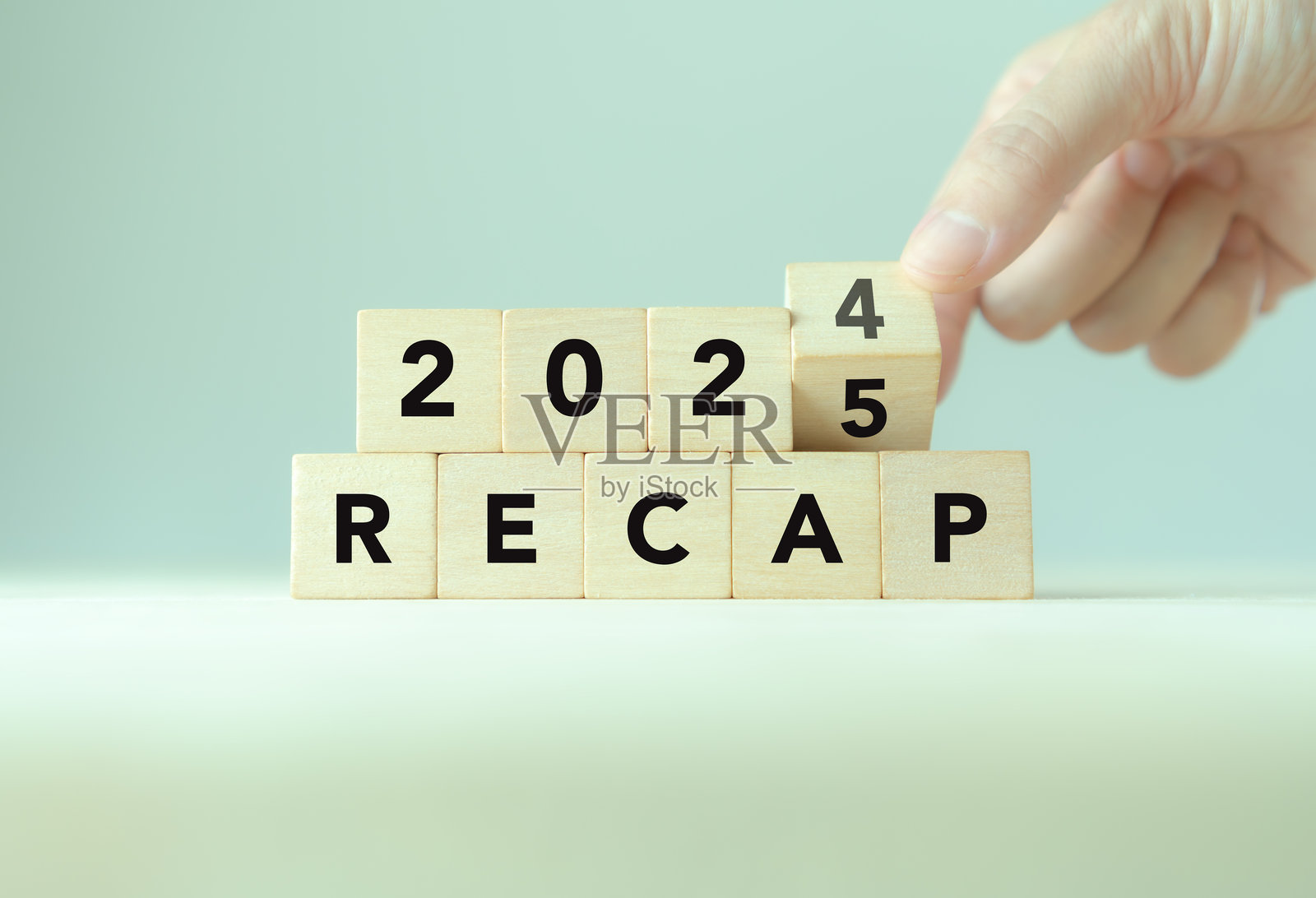 2024年经济、商业、金融概念回顾。2025年的商业规划。木块上的“回顾”文字和手部翻转2024到2025的木块，背景为简约灰色，留有空白。照片摄影图片