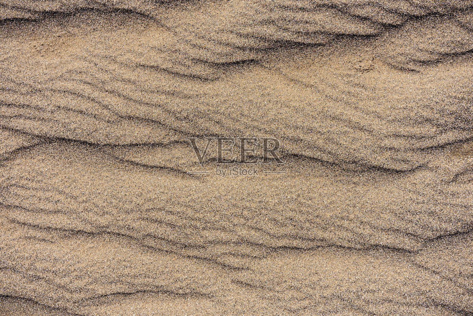 沙滩上的沙质纹理形成波浪状线条，展现出美丽的自然质感，具有极大的艺术趣味和抽象特征。照片摄影图片