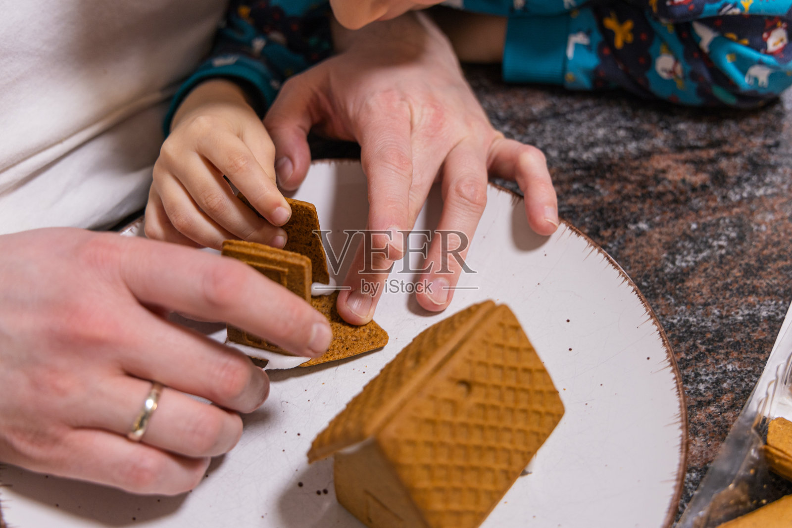孩子和父亲一起制作姜饼屋。圣诞节和新年假期。照片摄影图片