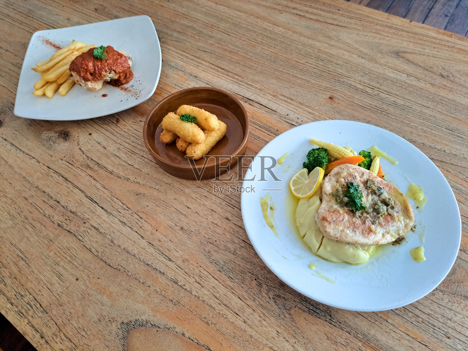 鸡肉皮卡塔配鸡排、柠檬黄油和刺山柑酱。炸面糊奶酪马苏里拉棒。香料腌制的鸡肉佩里佩里配辣味酸酱。菜单。照片摄影图片