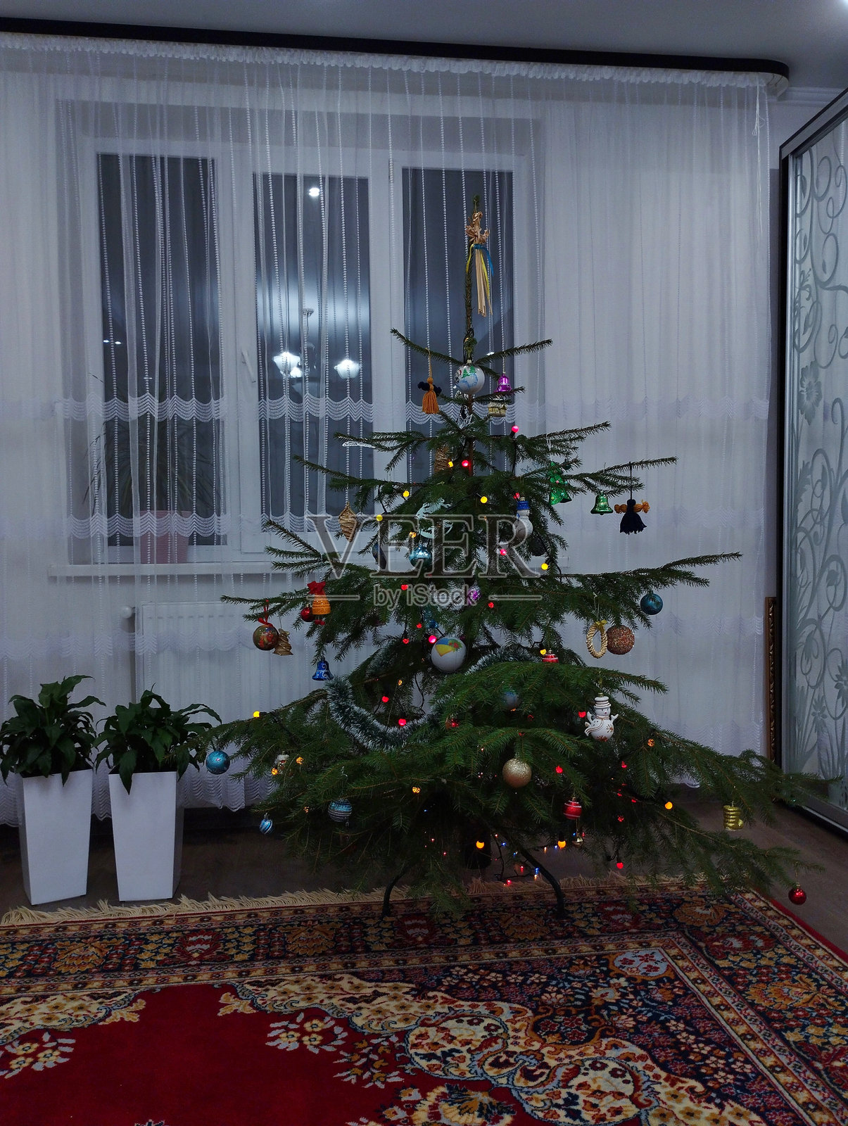 室内垂直照片中的圣诞树，装饰着圣诞装饰品和花环。照片摄影图片