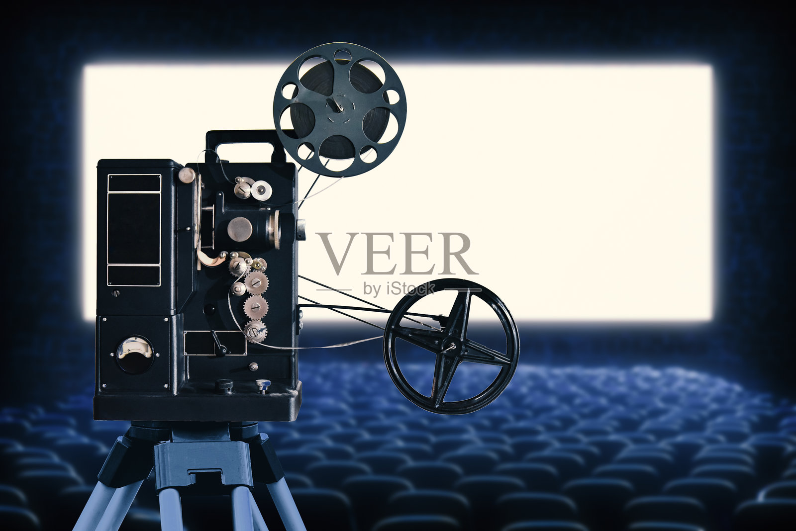 一台古董电影放映机在电影院的白色空白屏幕前。照片摄影图片