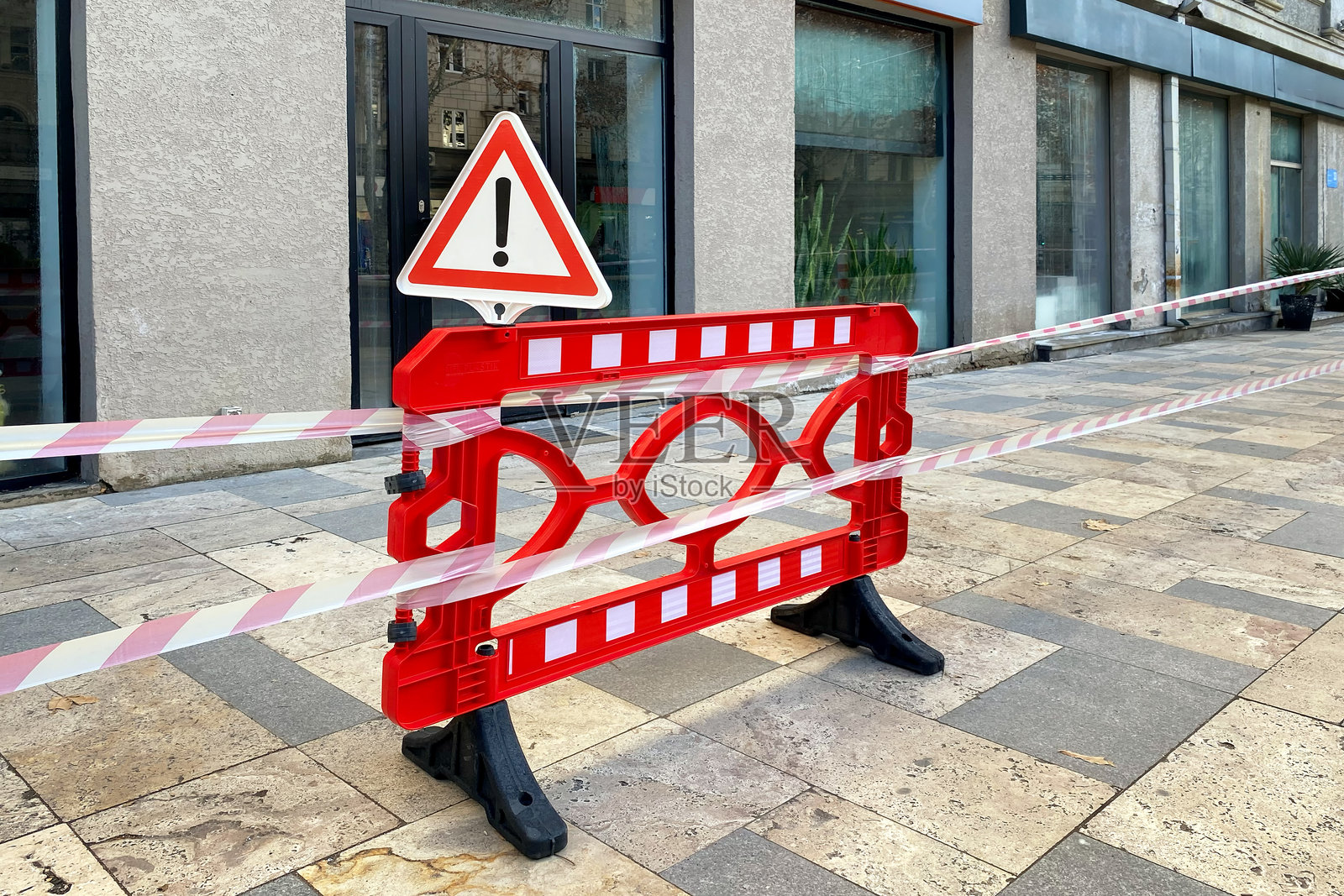 红色障碍物上拉伸的塑料带。禁止进入建筑。照片摄影图片