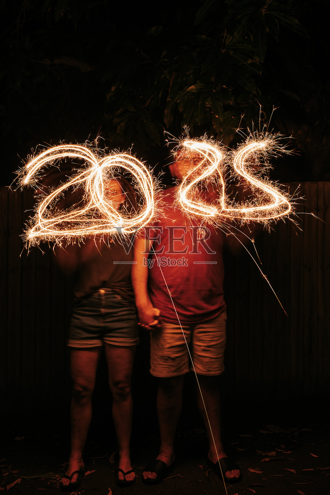 两个人用烟花棒写出数字2025照片摄影图片