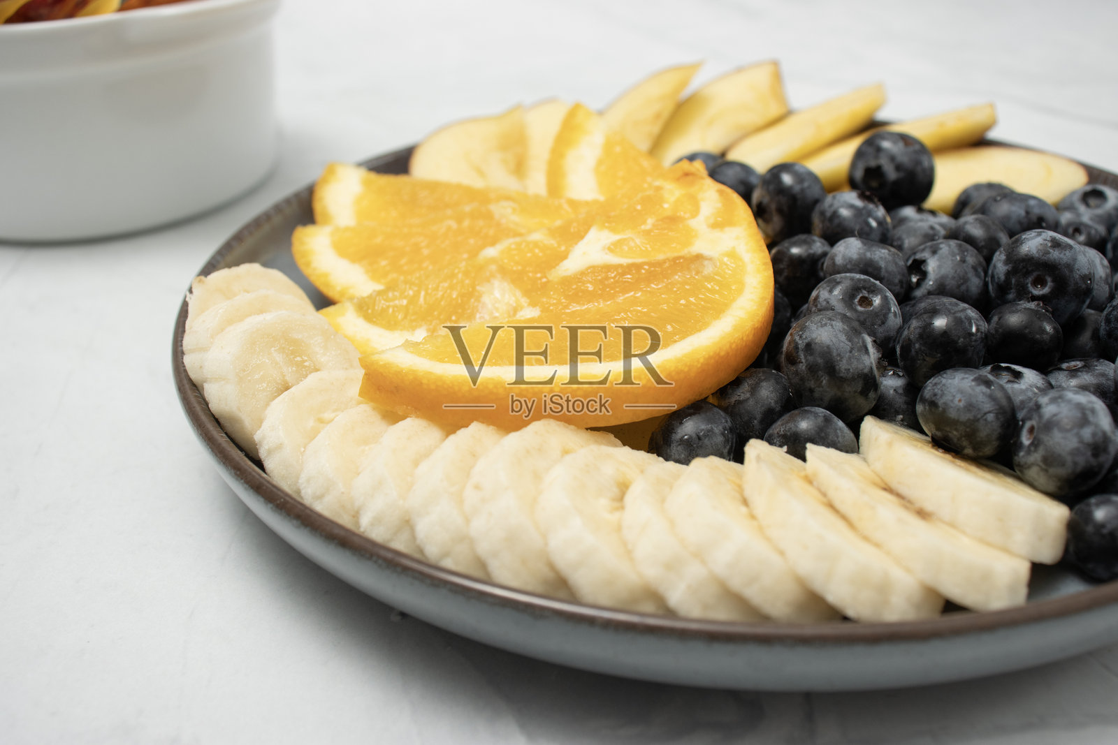 从上方俯视的早餐摆盘，包含新鲜水果、果汁、蓝莓、橙子片、苹果片、香蕉和葵花籽，整齐地摆放在盘子上。注重饮食和均衡饮食，促进积极的日常开始。照片摄影图片