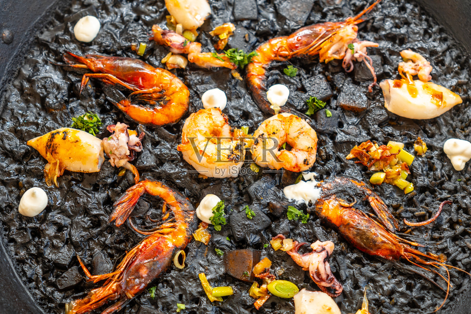 美味的黑米海鲜饭，配有烤虾和鱿鱼，产自马洛卡照片摄影图片